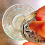 ツナ缶の蓋を指でおさえ油をきっている写真