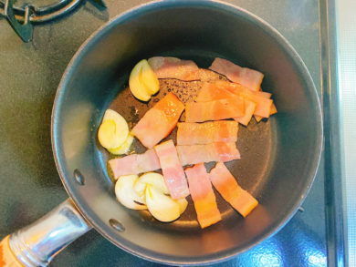 鍋でにんにくとベーコンを炒めている写真