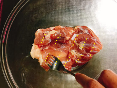 鶏モモ肉にフォークで穴をあけている画像