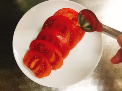 スライスしたトマトにオリーブ油をかけている画像